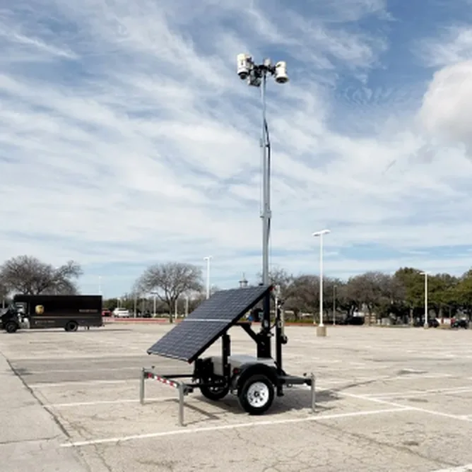 Solar surveillance trailer with extended camera mast parked on a lot
